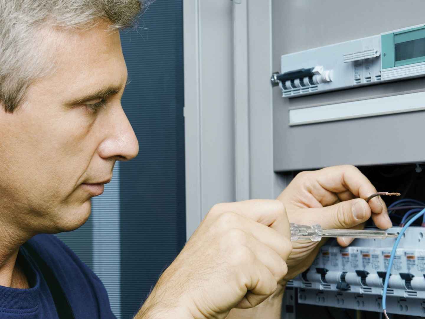 Ein Elektriker arbeitetet am Stromkasten