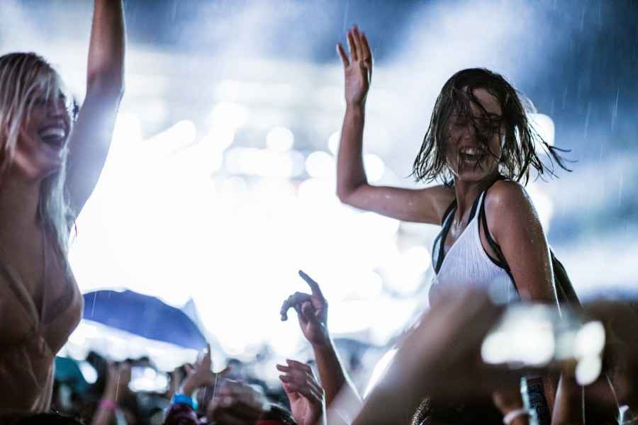 Zwei Frauen feiern auf einem Rock Konzert und es regnet. 
