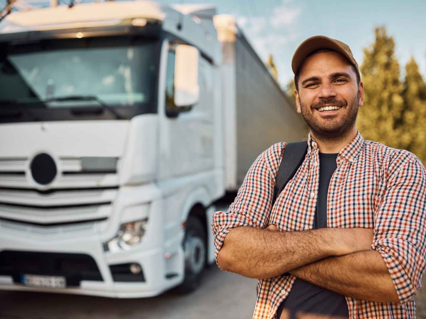 Ein Mann steht lächelnd neben einem LKW. 
