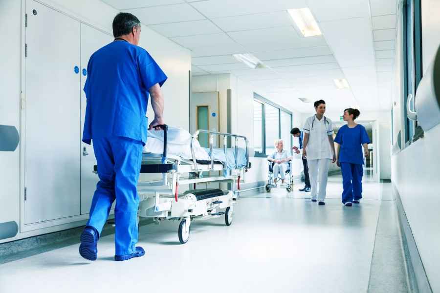 Pfleger im Krankenhaus schiebt Bett