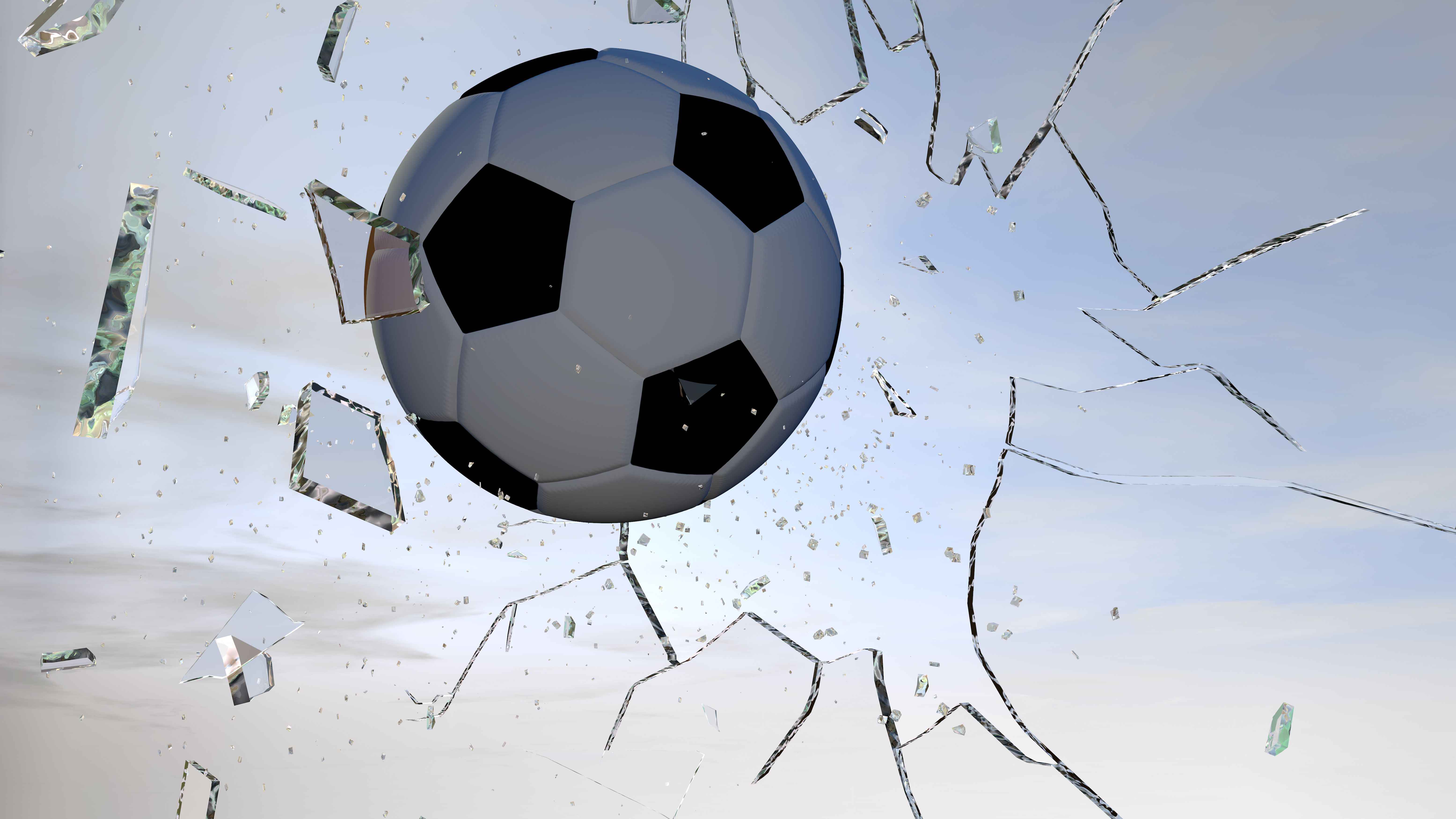 Fussball fliegt durch eine Glasfensterscheibe und zertrümmert diese.