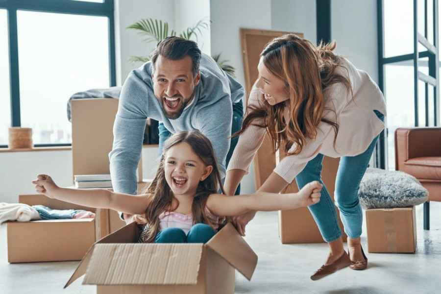 Eine Familie ist in ein Haus gezogen. Vater, Mutter und die Tochter haben Spaß beim Umzug.