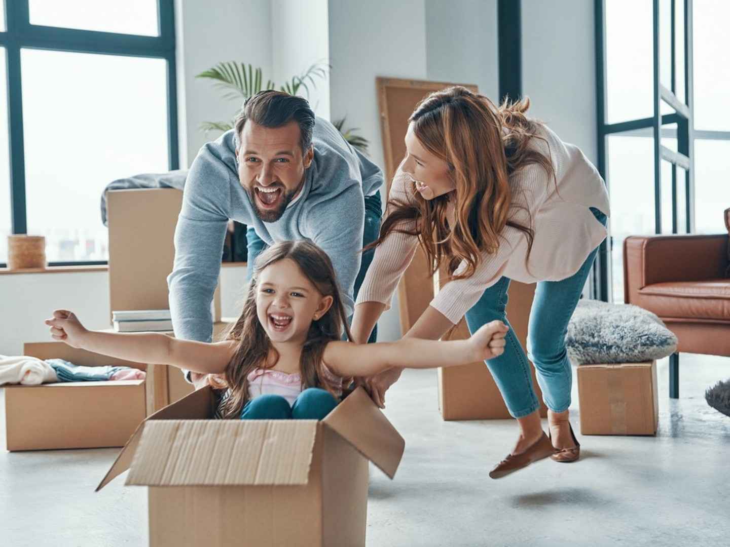 Eine Familie ist in ein Haus gezogen. Vater, Mutter und die Tochter haben Spaß beim Umzug.