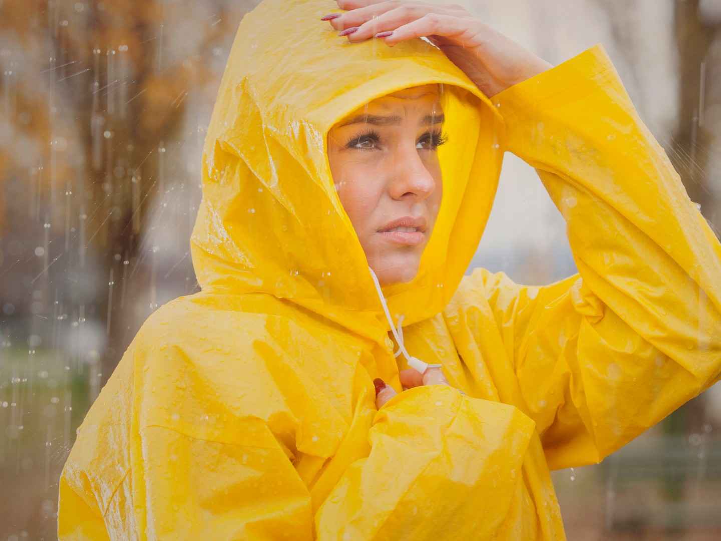 Gothaer Sturmversicherung: Junge Frau mit gelber Regenjacke ist bei Sturm unterwegs.