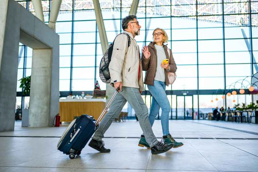 Zwei Personen laufen mit ihrem Gepäck durch einen Flughafen.