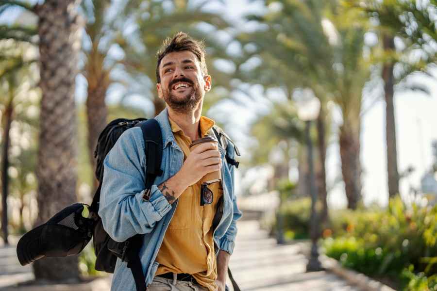 Ein Mann mit Rucksack ist im Urlaub und trinkt Kaffee.