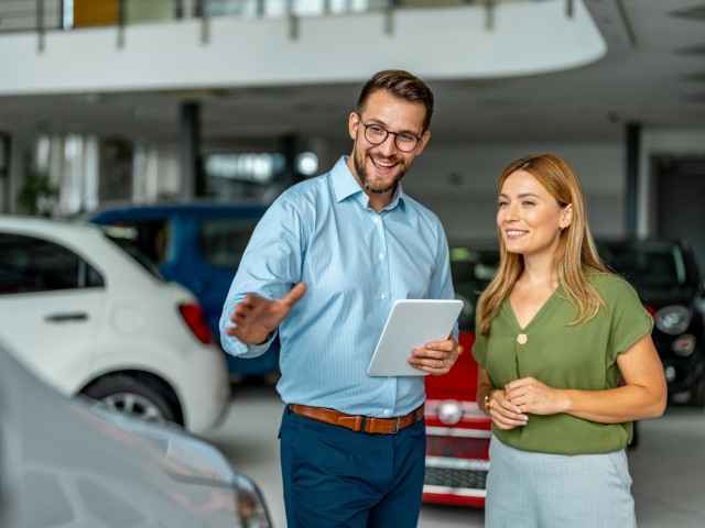 Gothaer Ratgeber Auto Leasing: Ein Mann führt ein Beratungsgespräch mit einer Frau in einem Autohaus.