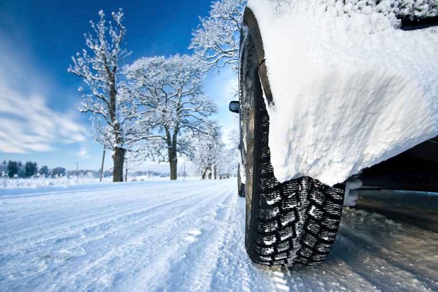 Ein Auto mit Winterreifen fährt über eine schneebedeckte Straße