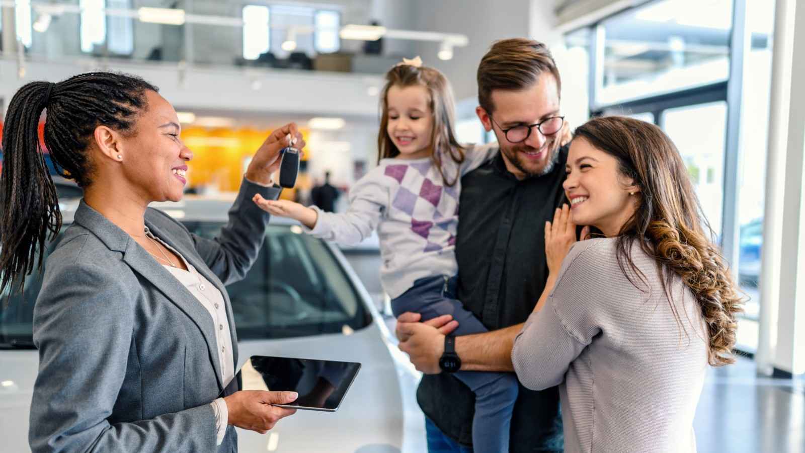 Eine Familie ist in einem Autohaus und bekommt einen Autoschlüssel überreicht.